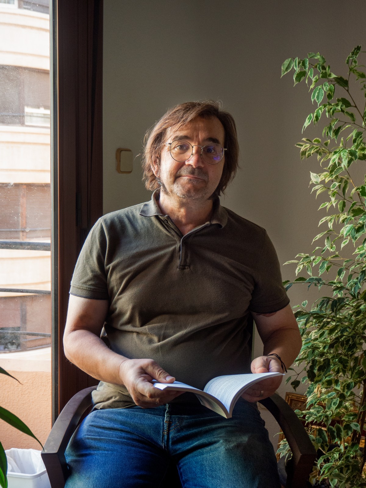Pablo Vila Arteaga, sentado junto a una ventana, con un libro abierto entre las manos.
